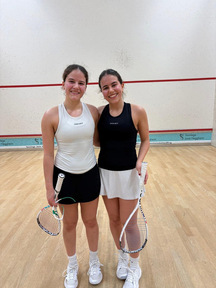 Two women smiling on a squash court in Dessard
